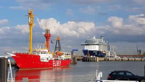 een rode boot is aangemeerd naast een cruiseschip bij Residenz Trossenstek in Cuxhaven