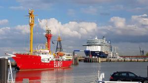 a red boat is docked next to a cruise ship at Residenz Trafalgar in Cuxhaven