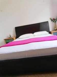 Una cama con una manta negra y rosa. en SHARED ROOMS NEAR ACROPOLIS AND MONASTIRAKI en Athens