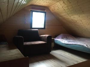 Habitación con silla y cama en el ático en Domek na Skarpie, en Sztutowo