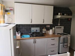 a small kitchen with white cabinets and a sink at 'Le Chalet II' free unlimited wifi 2 bed chalet House in Pembrokeshire