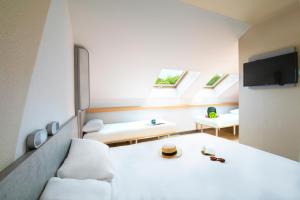 ibis budget Grenoble Voreppe في فوريب: غرفة بيضاء مع سرير وأريكة