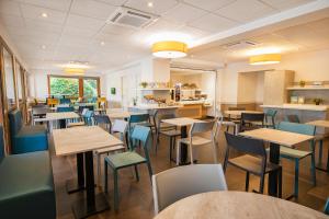 un restaurant avec des tables, des chaises et un comptoir dans l'établissement ibis budget Grenoble Voreppe, à Voreppe