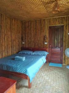 a bed in a room with a wooden wall at Nana Bungalows in Ban Tan