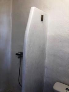 a bathroom with a toilet in a white wall at Salty Kisses and Sandy Toes in Firopótamos