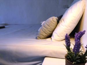 a bed with white sheets and pillows and purple flowers at Salty Kisses and Sandy Toes in Firopótamos