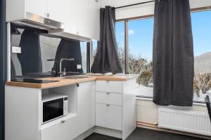 a kitchen with white cabinets and a sink and a window at Snowy Gums Smiggins in Perisher Valley