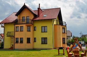 a large yellow house with a red roof at Jantar in Ostrowo