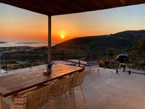 a patio with a wooden table and chairs and the sunset at Sun House Paros in Kampos Paros
