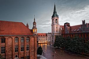 a city street with buildings and a clock tower at Apartamenty pocztowe in Toruń