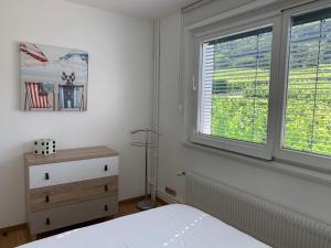 a bedroom with a bed and two windows at Gite Les deux belettes in Riquewihr