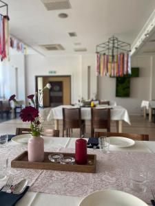 una mesa con platos y un jarrón con flores. en Hotel Alpex, en Zabrze