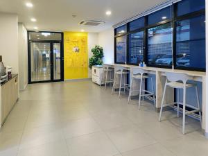 a lobby with a bar with stools and a yellow wall at Hop Inn Nan in Nan