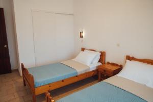 two twin beds in a room with two tables at Pagonia Apartments in Arillas