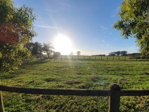 a fence in a field with the sun in the sky at bird haven self catering 
