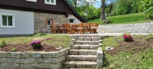 a patio with a stone wall and a bench and flowers at Chalupa U Smrku in Horní Polubný