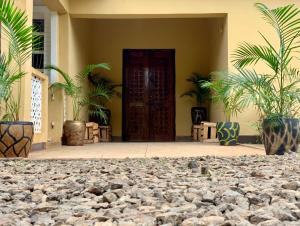 a building with a door and some plants and rocks at Pazuri Hostel in Moshi