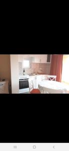 uma cozinha com armários brancos e um forno com placa de fogão em Apartmani Tanja em Tivat