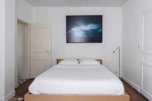 una camera con un letto bianco e una foto a parete di Veeve - Picture Postcard a Parigi