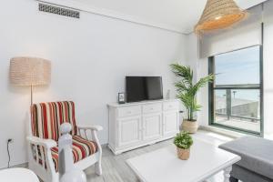 ein Wohnzimmer mit einem TV und einem Stuhl in der Unterkunft MONKÓ INFINITY in Torremolinos