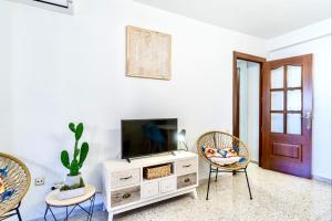 ein Wohnzimmer mit einem TV und 2 Stühlen in der Unterkunft Trendy Homes El Puerto de Almería- Muy próximo Playa y Centro Wifi gratis in Almería