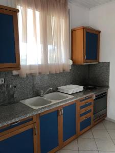 a kitchen with two sinks and blue cabinets and a window at Konstantina's House I in Koroni