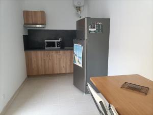 a kitchen with a stainless steel refrigerator and a table at La Grimodière in Ranville