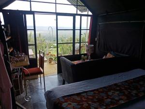 a bedroom with a bed and a couch and a window at Lemon Valley Farm in Elmenteita