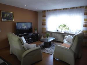 a living room with two chairs and a flat screen tv at Ferienwohnung Hagebuttenweg in Thale