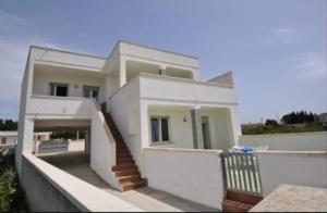 a white house with a staircase in front of it at Gallipoli Mancaversa Futura Vacanza Andrea in Marina di Mancaversa