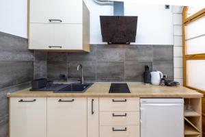 una cocina con armarios blancos y fregadero en Family apartments - Guesthouse Vranješ, en Makarska