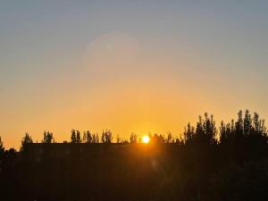 a sunset on a hill with trees in the foreground at Petit Studio Zen avec parking gratuit réservé in Houlgate