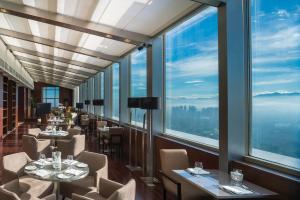 un restaurante con mesas, sillas y ventanas grandes en Marco Polo Ortigas Manila en Manila