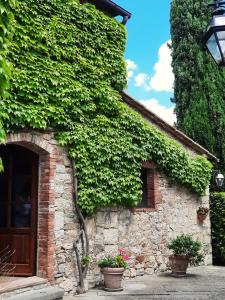 un edificio cubierto de hiedra con macetas. en Borgo Livernano - Farmhouse with pool en Radda in Chianti