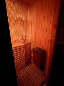 a small room with a wooden wall with a trash can at Dzivoklis ar saunu in Rēzekne