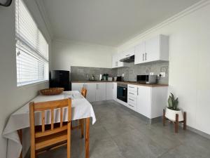 a kitchen with white cabinets and a table and chairs at AuobCorner in Walvis Bay