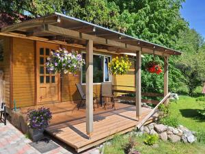 a wooden cabin with a deck in a yard at Atpūta namiņā pie jūras Skujiņas in Lembuži