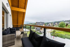 a balcony with couches and a table and a view at ApartHost Apartamenty Butorowy & Spa in Kościelisko