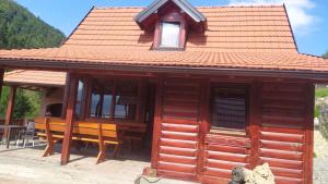 una baita di tronchi con un tavolo e sedie di fronte ad essa di Zaovinski Raj2 Tara a Konjska Reka