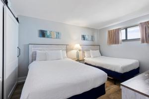 2 Betten in einem kleinen Zimmer mit 2 Fenstern in der Unterkunft Hosteeva 1-bedroom Meridian Plaza Condo with Ocean View in Myrtle Beach