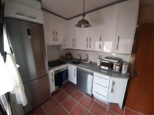 a kitchen with white cabinets and a red tile floor at La casa del puerto in El Arenal