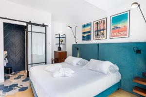 una camera da letto con un grande letto con cuscini bianchi di Victoria Boutique Hotel ad Arcachon