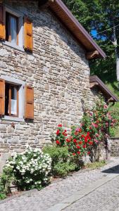 a stone building with flowers in front of it at La casina del Castiglione in Riolunato