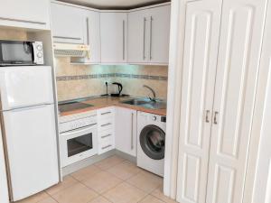 a white kitchen with a sink and a washing machine at Apartamento AKUNAMATATA con gran terraza, planta baja in Playa de San Juan