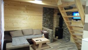 a living room with a couch and a wooden wall at Zaovinski Raj2 Tara in Konjska Reka