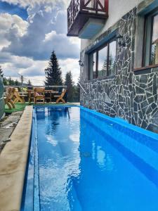 - une piscine d'eau bleue en face d'une maison dans l'établissement Pensiunea Piatra Graitoare, à Vartop