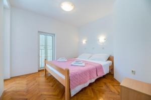 a white bedroom with a bed with a pink blanket at Apartments Melania & Antonia in Baška