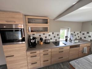 a large kitchen with wooden cabinets and a sink at Schillers Terrassen Fewo in Cottbus