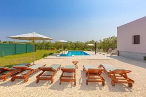een groep stoelen en een parasol en een zwembad bij Villa VIOLA with pool, whirlpool, playground & bbq in a olive grove with sea view, near the beach, Pomer - Istria in Pomer