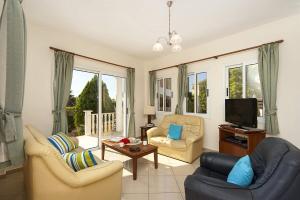 a living room with two chairs and a tv at Villa Gardenia by Villa Plus in Peyia